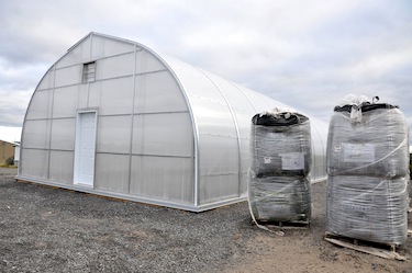 A second greenhouse has recently been constructed next to the original. Those bags of soil to its right will fill garden plots in time for the 2014 season. (PHOTO BY SARAH ROGERS)