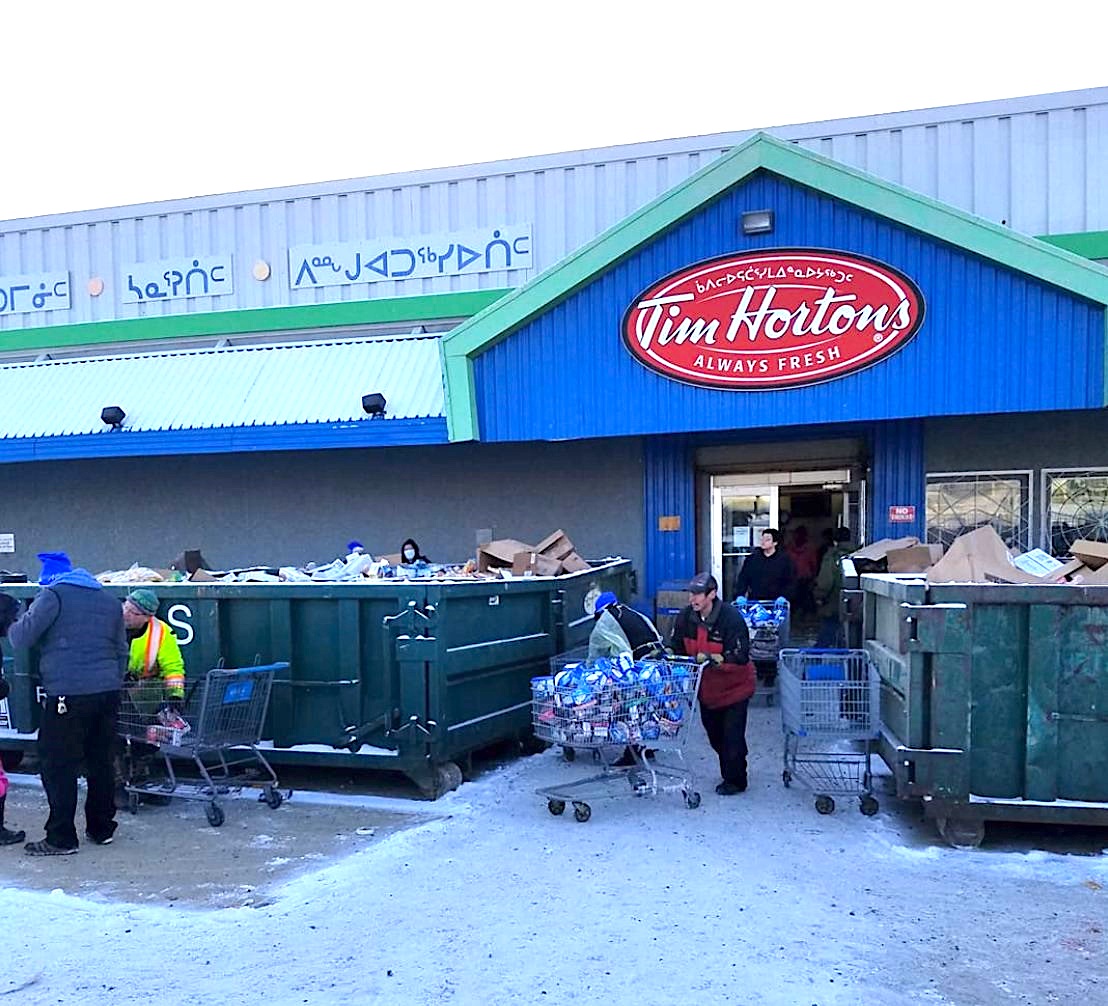 People empty damaged and contaminated stock from inside Iqaluit’s Northmart store in Iqaluit on Nov. 10. While the Nov. 8 fire completely destroyed its adjacent warehouse, the store sustained major smoke and water damage inside. (PHOTO BY JOANASIE AKUMALIK)