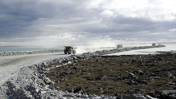 Massive 100-tonne trucks move rocks from a former lake bed over to a dike under construction. The Meadowbank's gold lies under lakes, which must be drained and dammed before the deposits can be mined.