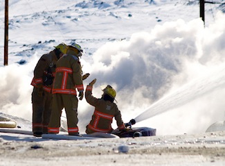Firefighters exchange a high five after more than eight hours battling a massive blaze that levelled a three-story apartment building in Iqaluit's Road To Nowhere subdivision March 24. (FILE PHOTO)