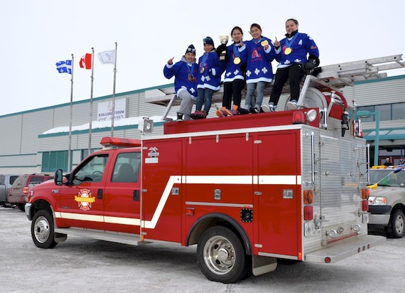 Kuujjuaq team members of Nunavik Nordiks pose on top of the Kuujjuaq Fire Dept. truck in front of their local arena, the Kuujjuaq Forum, on March 26. From left to right: Siqua Munick, Naomi Sala, Lucina Gordon, Nellie Cain-Snowball and Leanna Angnatuk, sporting their hockey jerseys and newly-acquired bling, a bright shiny heavy gold medal, as well as their trophy. The truck left the Kuujjuaq Forum and drove all around town before it ended at the Katittavik Town Hall. Read more about the team's recent win in Ottawa later on Nunatsiaqonline.ca. (PHOTO BY ISABELLE DUBOIS)