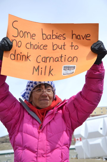 Organizer of the June 14 food protest, Leesee Papatsie, holds a sign at a protest held across the street from Northmart in Iqaluit. About a dozen people came out to raise awareness of overpriced and expired food in the North. (PHOTO BY DAVID MURPHY)