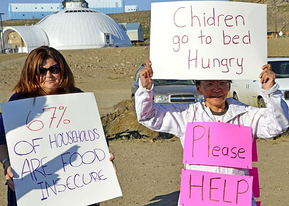 Leesee Papatsie (right) displays a sign protesting high food prices in Nunavut. The founder of the Feeding My Family Facebook group said she's encouraged the Auditor General of Canada's report on Nutrition North. (FILE PHOTO)