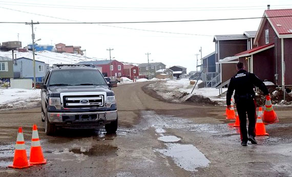 An Iqaluit bylaw officer removes barriers that blocked a street in Iqaluit's Happy Valley neighbourhood for nearly three days during an armed standoff between police and a distraught man this past May. (FILE PHOTO)