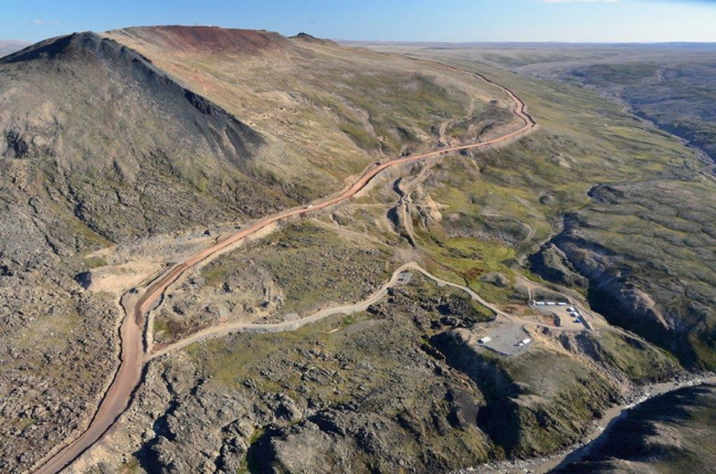 Iron ore from the Mary River mine is currently trucked from the top of Deposit 1 of the Naluujaak pit, top left, downhill to an ore crusher. The crushed ore is trucked about 100 km down a relatively flat tote road to the port at Milne Inlet. The short spur road in this photo leads to a small storage area in bottom right. (PHOTO COURTESY BAFFINLAND IRON MINES)