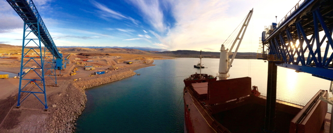 A view of the Milne Inlet shiploader from onboard the ship Federal Tiber. The reddish-brown piles in the distance on shore show iron ore stockpiles ready for shipping overseas. Under its early revenue phase, Baffinland is currently authorized to ship ore during the open ice season. (PHOTO COURTESY BAFFINLAND IRON MINES)