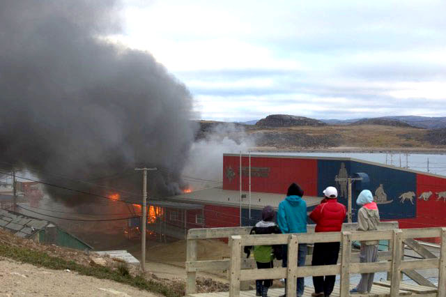 As of mid-morning Sept. 6, a major fire was eating its way through Peter Pitseolak School in Cape Dorset, likely on its way towards destroying the entire structure. Sources told Nunatsiaq News the fire broke out sometime between 2 a.m. and 3 a.m. After a dangerous fireball burst through a section of open roof at around 7 a.m., firefighters gave up on their attempts to save the building. The school — built in the late 1960s and renovated and expanded several times thereafter — served about 150 students attending Grade 7 to Grade 12 classes and employed a staff of about 20. Multiple sources told Nunatsiaq News that RCMP have apprehended two young people alleged to have been sniffing gasoline under the building prior to the fire. (PHOTO COURTESY OF JOHN CORKETT)