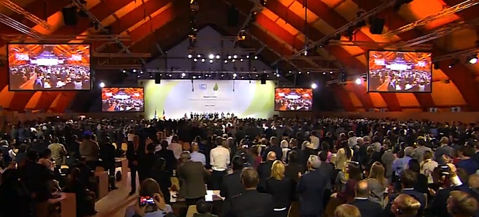 Delegates at the COP21 plenary listen Dec. 12 to comments from COP21 leaders urging them to accept a draft text and 