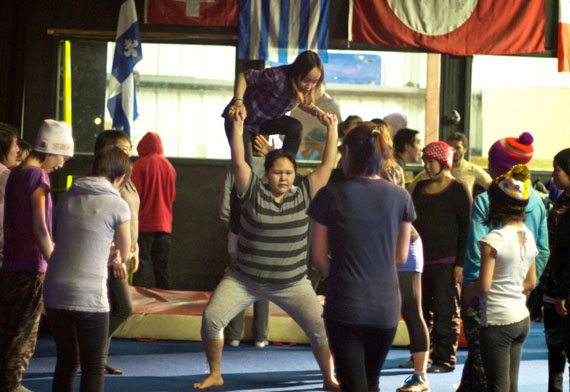 Long-time Igloolik Artcirq performer and instructor Reena Qulitalik attempts to balance a young performer on her shoulders. Artcirq is hosting the workshops for about 70 youth in Igloolik over a two-week period. (PHOTO BY GISELE HENRIET)