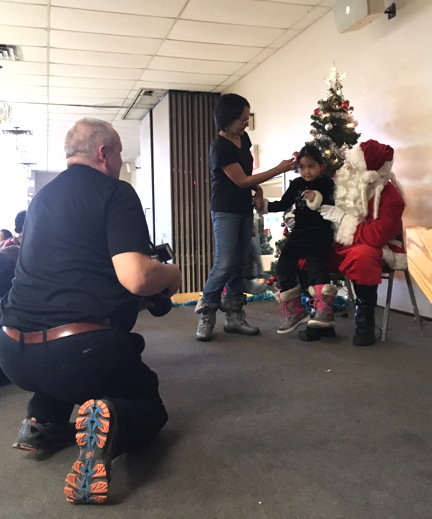 Sgt. Chris Hrnchiar, left, taking photos of children with Santa Claus at the Tungasuvvingat Inuit Christmas party.