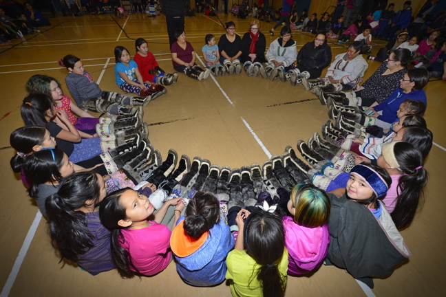 Students, staff members and others at Alookie Elementary School in Pangnirtung make a sealskin kamik circle in the school gym Jan. 28 at a seal celebration event following a seal theme at the school that lasted more than two weeks. Alookie principal Lena Metuq explained how the entire school took part in numerous activities pertaining to seal that began with elders carving up four donated seals at the school. Students learned the different parts of the seal from elders and also how to clean, dry and soften sealskin so it can be sewn into garments. They also watched a film on the history of Pangnirtung, Metuq said, so students can understand the town's evolution. The school's seal unit ended with a feast where students, staff and community members were invited to show off their sealskin clothing. (PHOTO BY DAVID KILABUK)