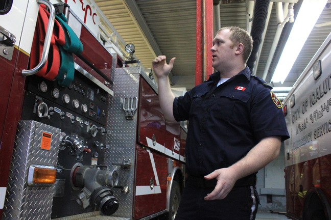 Lt. Matthew Edmunds of Iqaluit Emergency Services explains how the fire truck's pump works at the fire hall Jan. 20. (PHOTO BY LISA GREGOIRE)