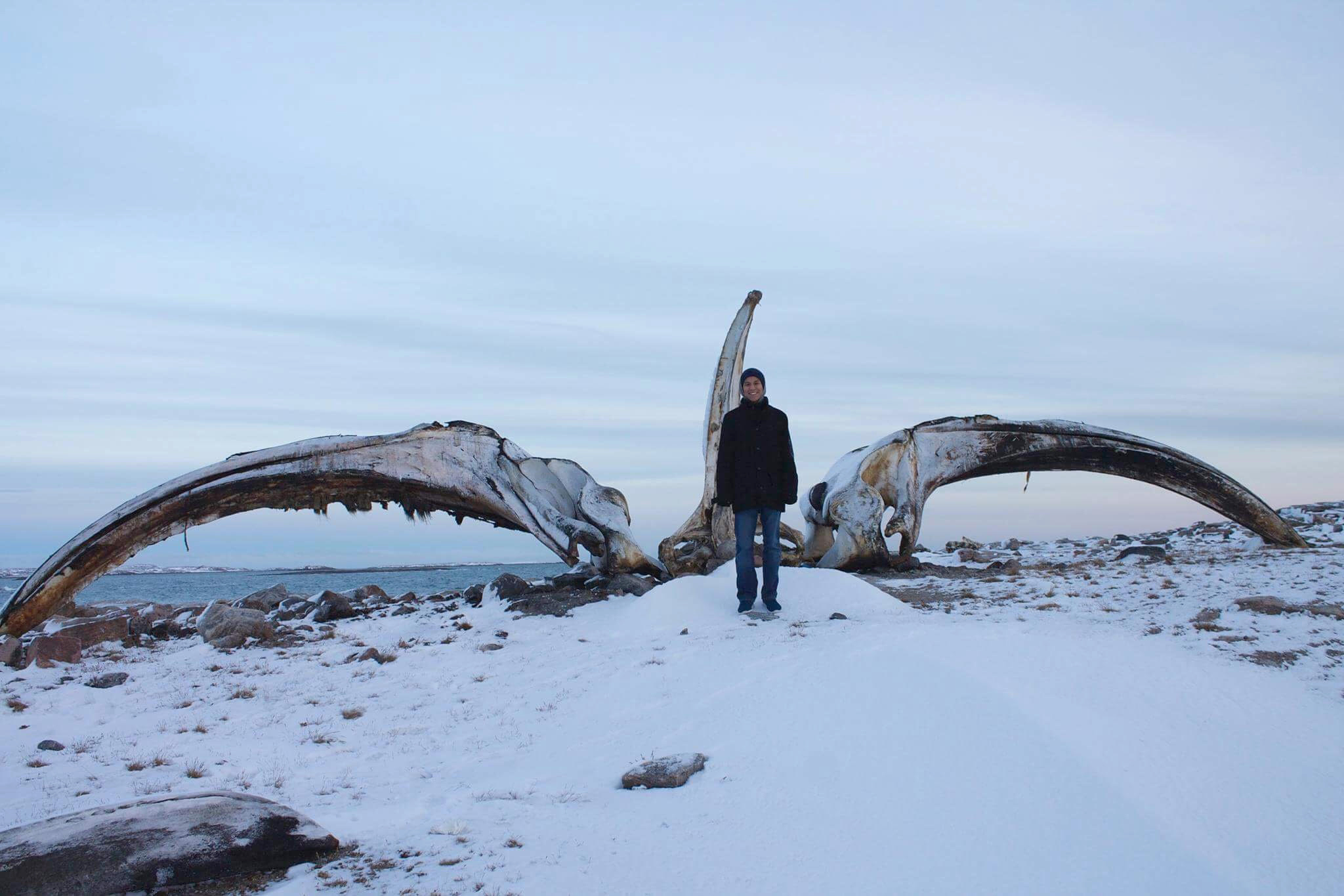 Alex Angnaluak stands in front of a bowhead whale jaw on a visit to Naujaat last year. (HANDOUT PHOTO)