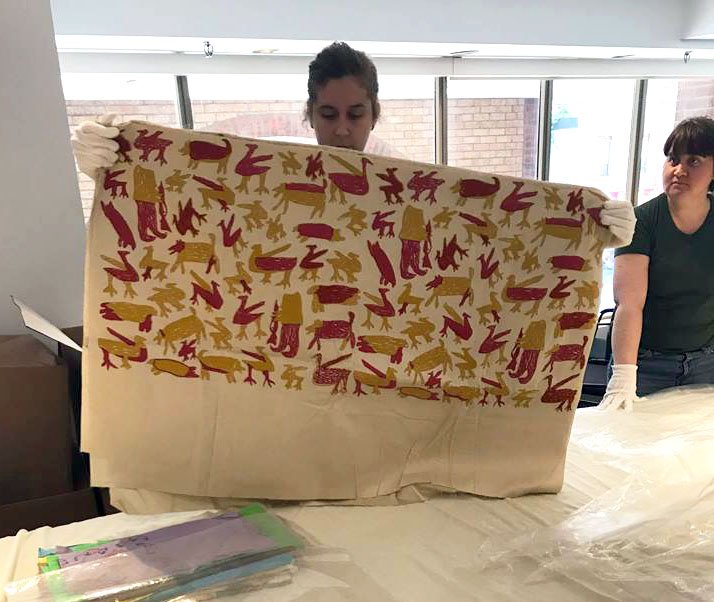 A curator holds up one of 175 printed fabrics created in Cape Dorset in the 1960s and 70s and recently uncovered by Dorset Fine Arts. The pieces have been donated to the Textile Museum of Canada, which plans to open an exhibit of them by 2019. (PHOTO COURTESY OF DORSET FINE ARTS)