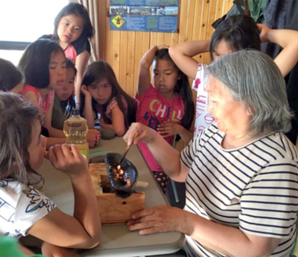 An elder lights the qulliq with schoolchildren in Nunavik last summer. Kativik Ilisarniliriniq and Frontier College are offering literacy camps again this summer for school-age children in 12 communities: Kuujjuarapik, Umiujaq, Inukjuak, Puvirnituq, Ivujivik, Salluit, Kangiqsujuaq, Quaqtaq, Kangirsuk, Aupaluk, Tasiujaq and Kuujjuaq, starting July 9. The camps are designed to promote literacy in Inuktitut, English and French and help students ages 5-12 maintain the skills they learned during the school year. There’s still room to register by visiting your child’s local school. (PHOTO BY FRONTIER COLLEGE) 