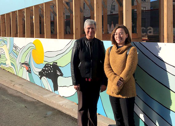 Kaley Sheppard, right, stands with Darlene Coward Wight, curator of Inuit art at the Winnipeg Art Gallery, on Friday, Sept. 21, near a wooden structure that was built to protect part of the sidewalk on Memorial Blvd, in front of the gallery. The WAG asked Sheppard to design a mural on the outside of the structure as part of the 2018 Wall-to-Wall Mural + Culture Festival. The mural is titled “Mosaic Sea.” Sheppard said “this work was created by putting Inuit-style imagery together through a collage-based process. I see the process of layering the imagery as a metaphor for the building of self, as I add and shed layers to my life through time.” Sheppard, an emerging artist, whose father comes from Nunatsiavut, lives and creates art in Winnipeg. The outdoor art installation will exist on Memorial Blvd. for a year or more, until the opening of the WAG Inuit Art Centre in 2020. (PHOTO COURTESY OF THE WAG)