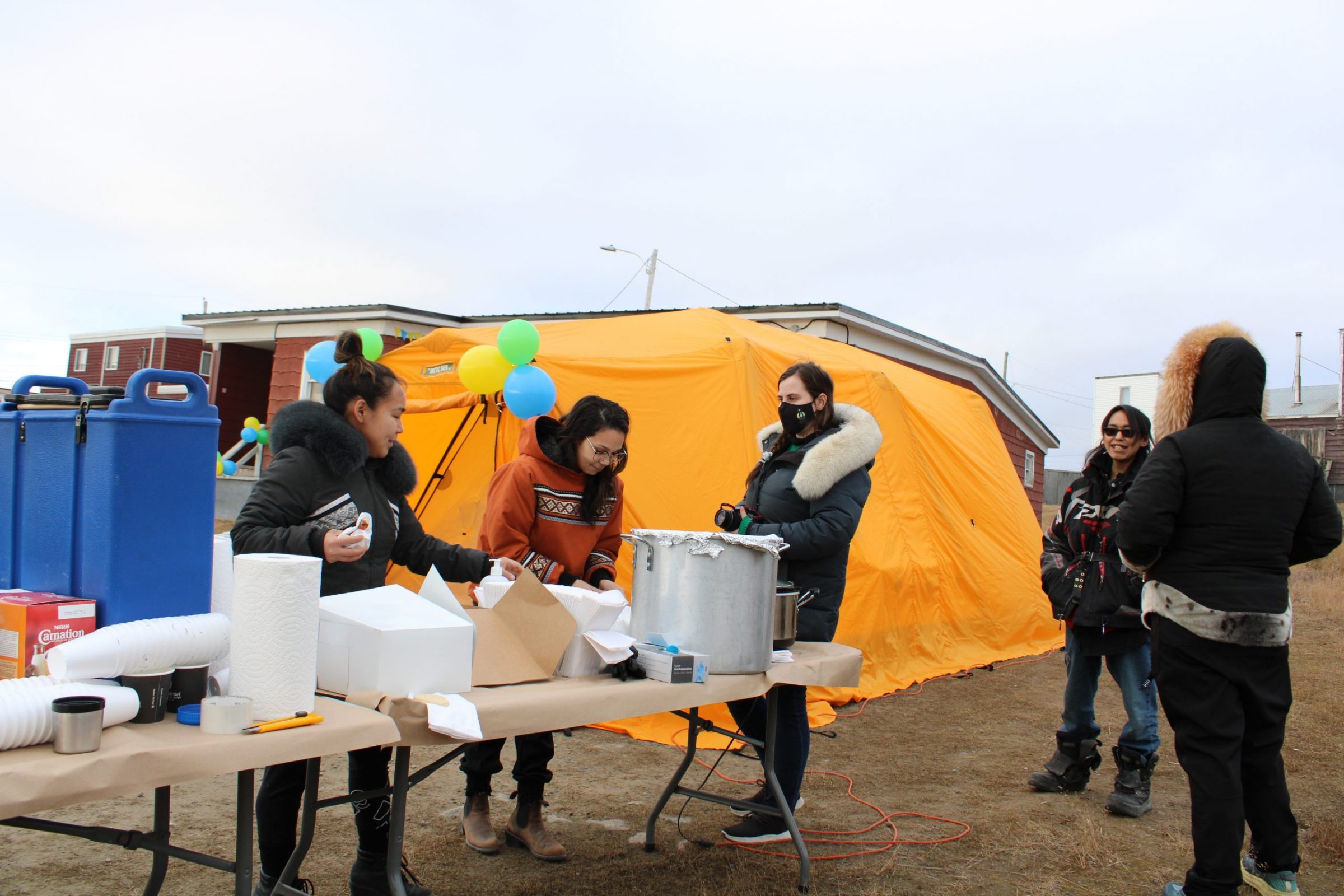 The Qaujigiartiit Health Research Centre celebrates its 15th birthday by serving caribou stew to Iqaluit residents on Tuesday. From left: Nina Kuppaq, Nubiya Enuaraq, Qaujigiartiit’s program evaluator Lauren Nevin and Clayton Sanguya. Attendees also got a look at plans for the proposed Inuusirvik Community Wellness Hub, enter a draw, contribute to a poster about what wellness means to them and take home free backpacks and hats. (Photo by David Venn)